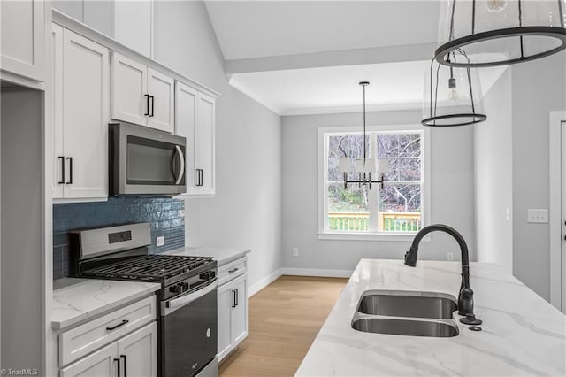kitchen featuring baseboards, white cabinets, tasteful backsplash, a sink, and stainless steel appliances