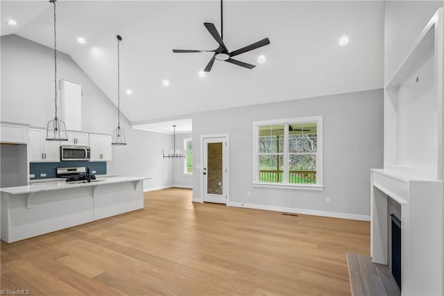 unfurnished living room featuring ceiling fan, visible vents, a fireplace, light wood-type flooring, and high vaulted ceiling