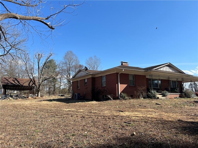 view of property exterior with central air condition unit, covered porch, a chimney, and brick siding