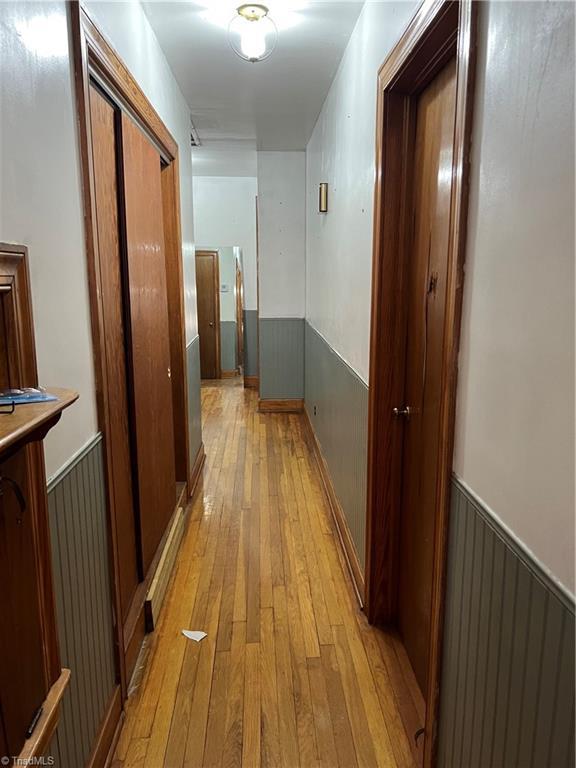 hall with light wood-type flooring and wainscoting