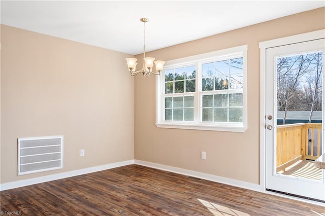 empty room with a chandelier, visible vents, dark wood-type flooring, and baseboards