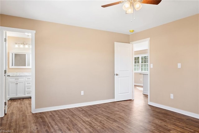 unfurnished bedroom with dark wood finished floors, ceiling fan, baseboards, and connected bathroom