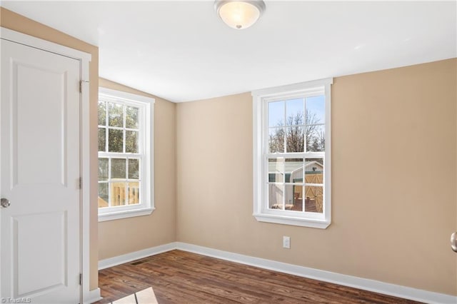 unfurnished room featuring baseboards, wood finished floors, and vaulted ceiling