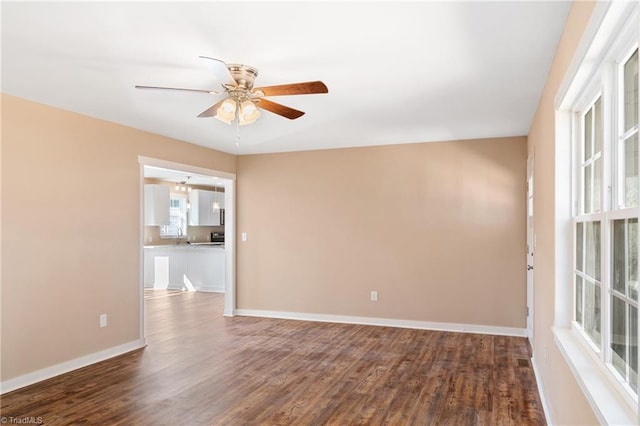 unfurnished room with a ceiling fan, baseboards, and dark wood-style flooring