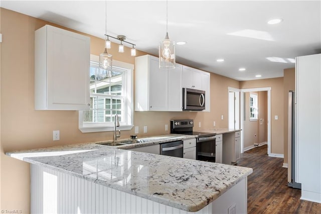 kitchen featuring appliances with stainless steel finishes, light stone countertops, a peninsula, and a sink