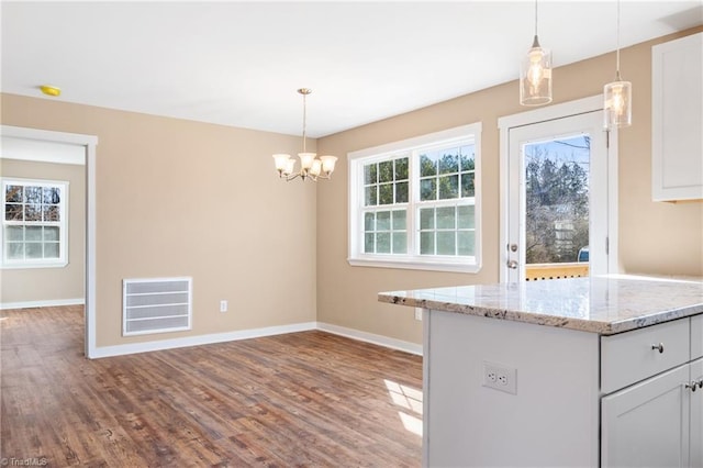 kitchen with visible vents, dark wood-style floors, hanging light fixtures, baseboards, and light stone countertops