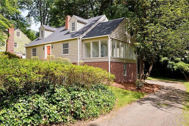 515 N Pine Valley Rd N, Winston-Salem, NC 27106 - view of front facade featuring a chimney, a sunroom, driveway, and roof with shingles