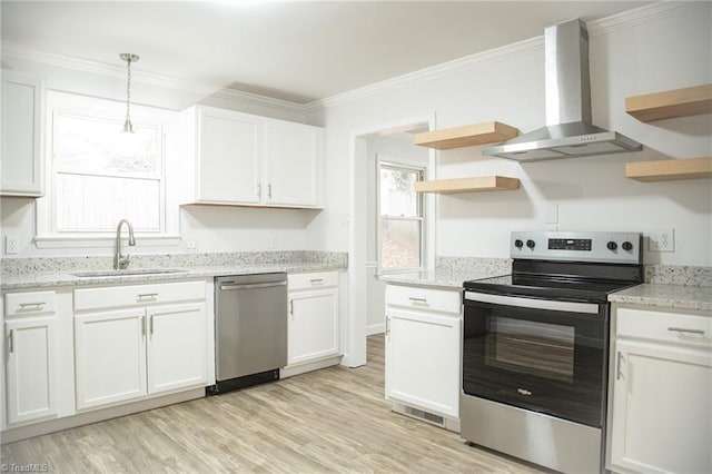 kitchen with white cabinets, wall chimney exhaust hood, stainless steel appliances, and decorative light fixtures