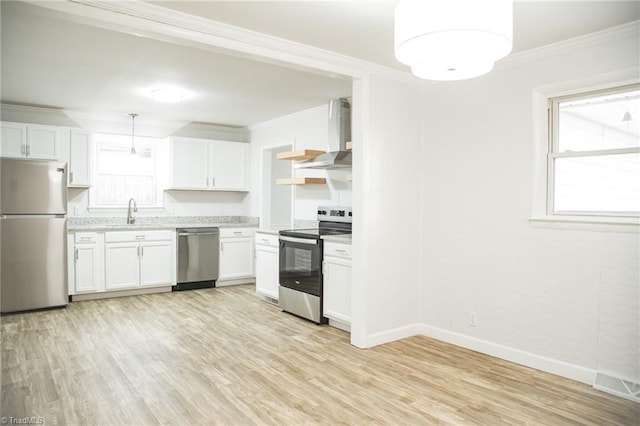 kitchen featuring stainless steel appliances, wall chimney range hood, light hardwood / wood-style flooring, white cabinetry, and hanging light fixtures