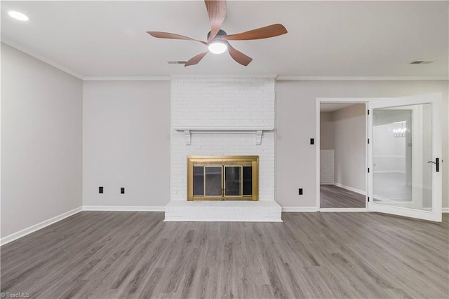 unfurnished living room with ceiling fan, ornamental molding, a brick fireplace, and hardwood / wood-style floors