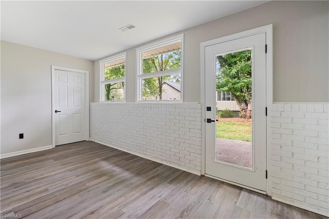 doorway to outside featuring brick wall and hardwood / wood-style floors