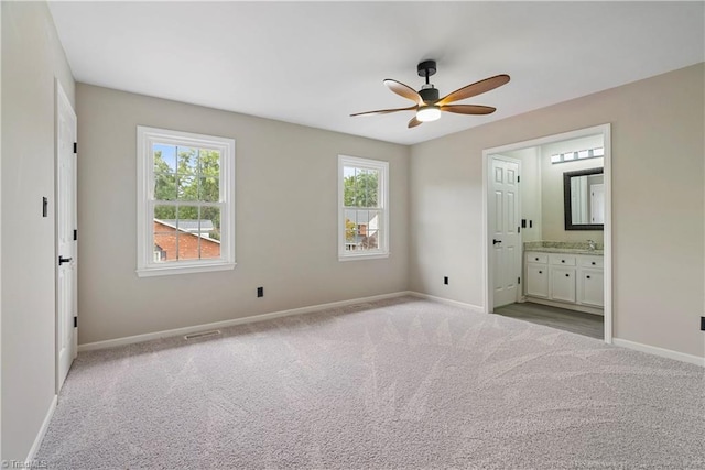 unfurnished bedroom with ceiling fan, light colored carpet, ensuite bathroom, and sink