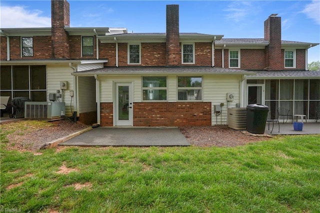back of property with a chimney, brick siding, a patio, central AC unit, and a sunroom