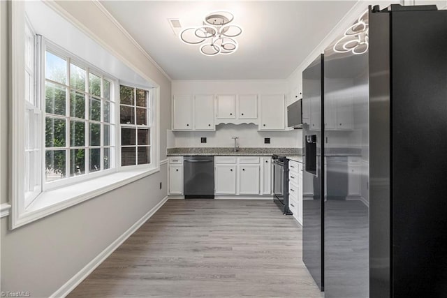 kitchen with a notable chandelier, appliances with stainless steel finishes, light hardwood / wood-style floors, and white cabinetry