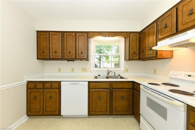 kitchen featuring white appliances, a sink, under cabinet range hood, light countertops, and brown cabinetry
