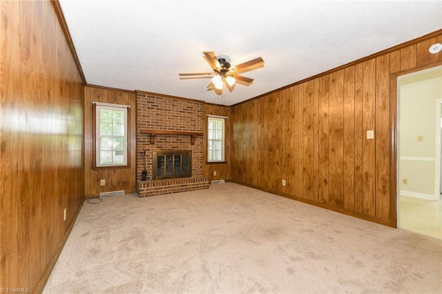 unfurnished living room featuring ceiling fan, ornamental molding, wood walls, plenty of natural light, and carpet flooring