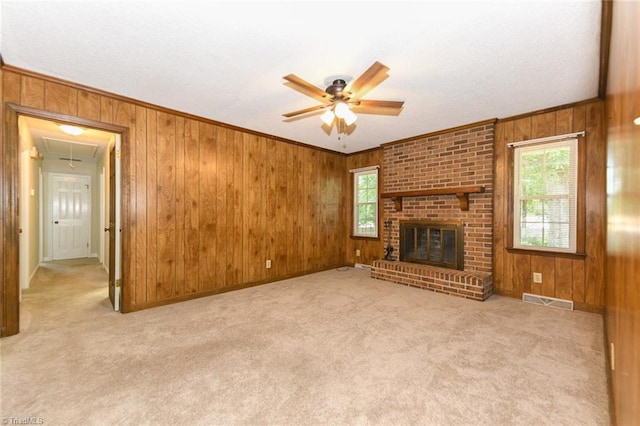 unfurnished living room featuring ceiling fan, attic access, wood walls, carpet, and crown molding
