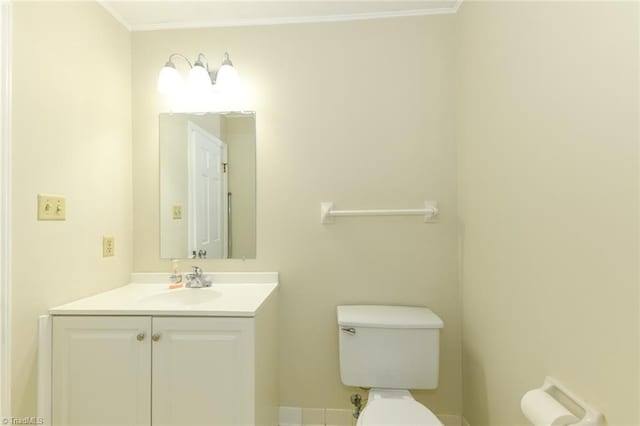 half bathroom with toilet, ornamental molding, vanity, and baseboards