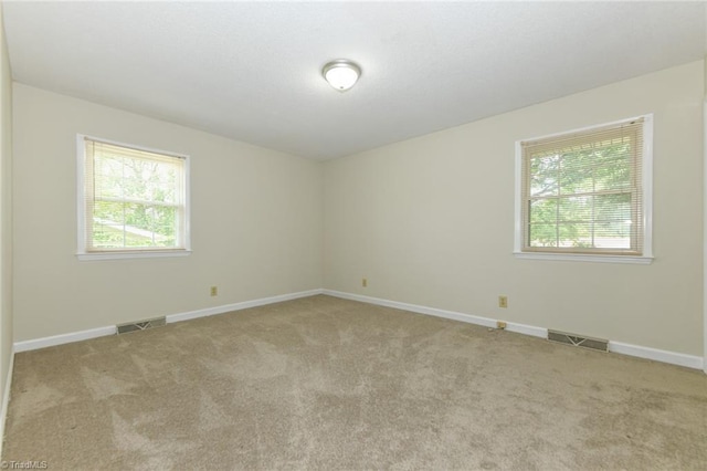 spare room featuring healthy amount of natural light, carpet flooring, and baseboards