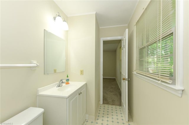 half bath featuring toilet, vanity, crown molding, and baseboards