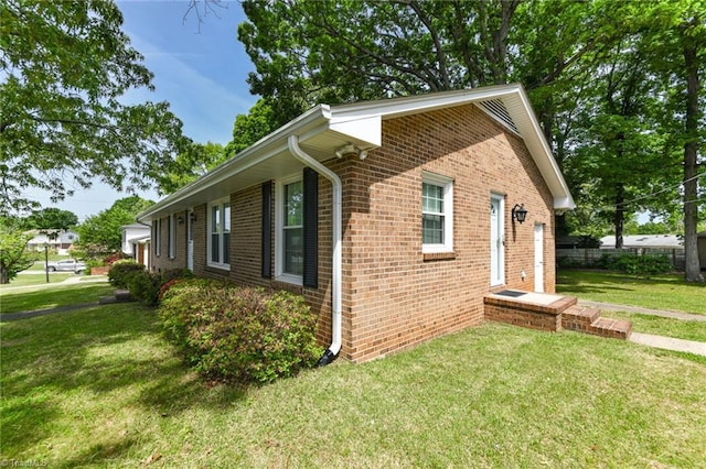 view of side of property featuring brick siding and a lawn