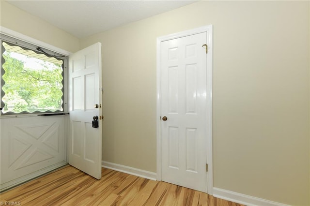 doorway with light wood-style flooring and baseboards