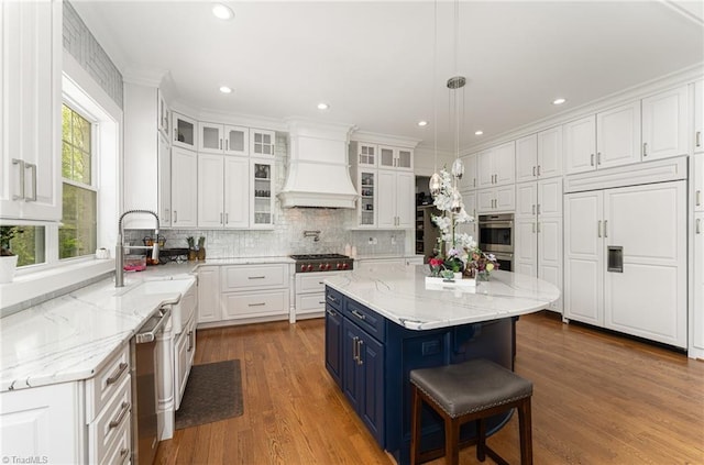 6323 Nesting Way, Oak Ridge, NC 27310 - kitchen with appliances with stainless steel finishes, white cabinetry, blue cabinetry, and premium range hood