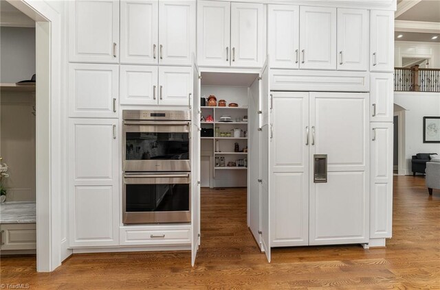 6323 Nesting Way, Oak Ridge, NC 27310 - kitchen featuring white cabinets, light wood-type flooring, stainless steel double oven, and ornamental molding