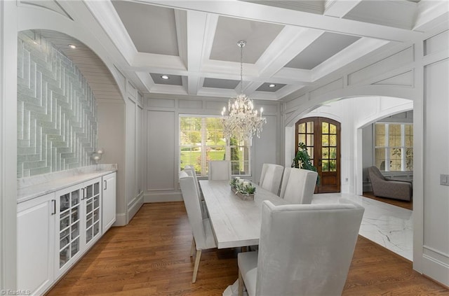 6323 Nesting Way, Oak Ridge, NC 27310 - dining area with coffered ceiling, an inviting chandelier, french doors, a decorative wall, and beam ceiling