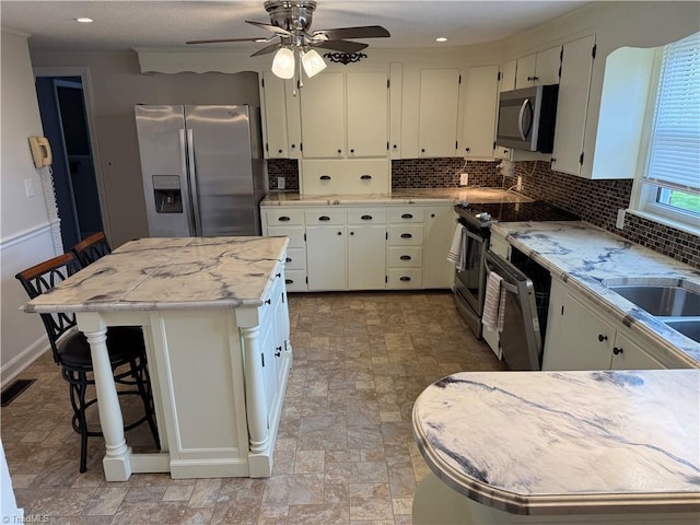 1632 Sanford Dr, Winston-Salem, NC 27105 - kitchen featuring visible vents, ceiling fan, white cabinetry, stainless steel appliances, and backsplash