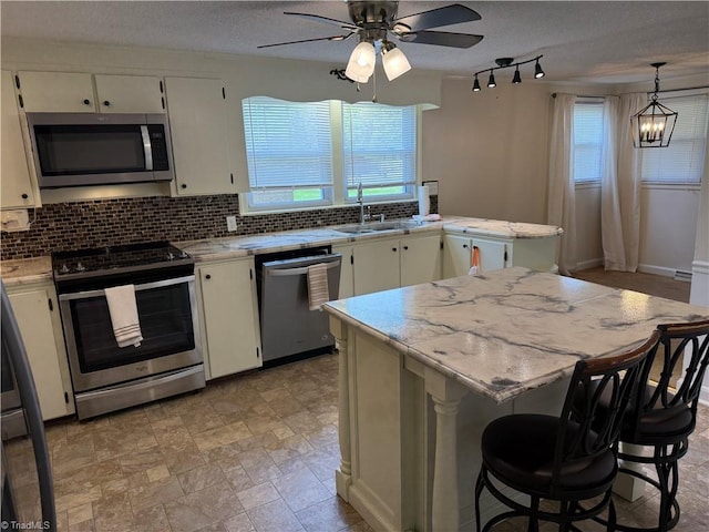 1632 Sanford Dr, Winston-Salem, NC 27105 - kitchen featuring decorative backsplash, ceiling fan with notable chandelier, a sink, and appliances with stainless steel finishes