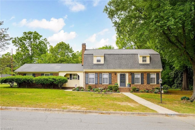 view of front of property with a front lawn, a chimney, and brick siding