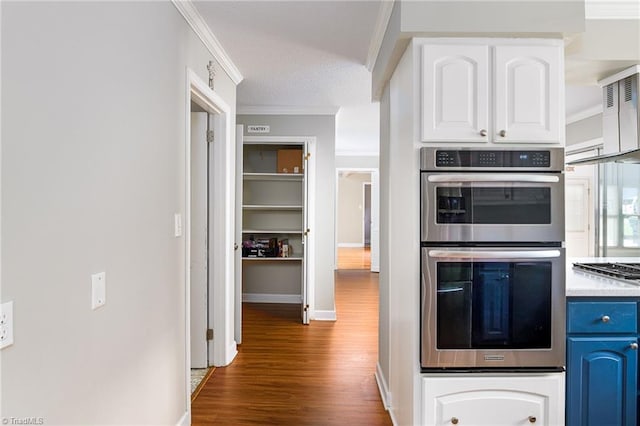 kitchen featuring white cabinetry, crown molding, blue cabinets, stainless steel double oven, and wood finished floors