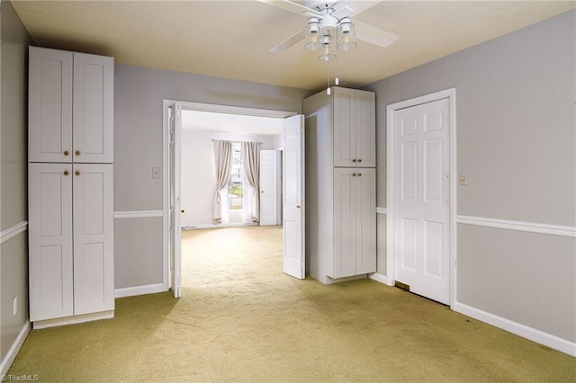 interior space featuring baseboards, a ceiling fan, and light carpet