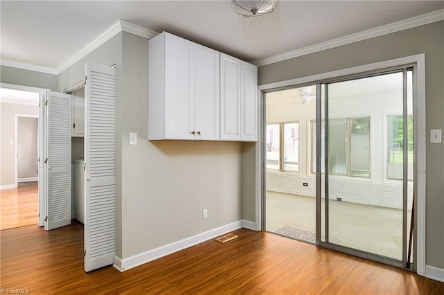 spare room with dark wood-style flooring, visible vents, crown molding, and baseboards