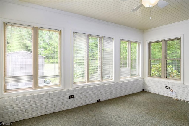 unfurnished sunroom featuring carpet, a healthy amount of sunlight, and crown molding