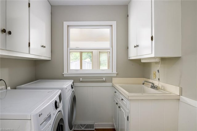 washroom with wainscoting, cabinet space, washing machine and clothes dryer, a sink, and visible vents