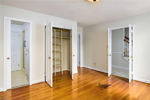 unfurnished bedroom with light wood-style floors, a closet, and baseboards
