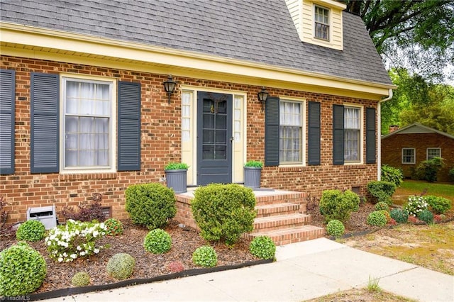 doorway to property featuring roof with shingles, crawl space, and brick siding