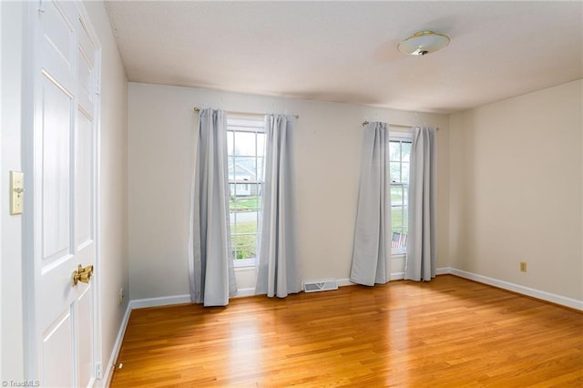 empty room with visible vents, baseboards, and light wood-type flooring