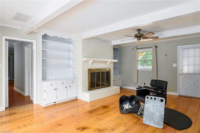 living area featuring beamed ceiling, visible vents, light wood-style flooring, baseboards, and ornamental molding