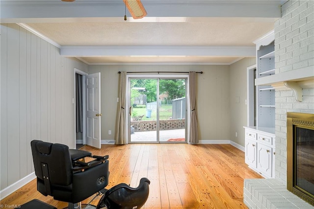 living area featuring light wood-style floors, ornamental molding, beamed ceiling, and a fireplace