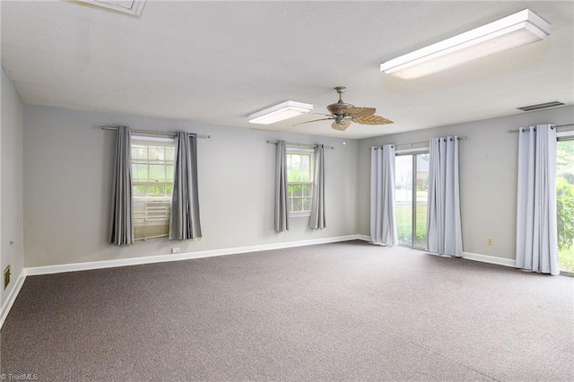 carpeted empty room with a ceiling fan, visible vents, and baseboards