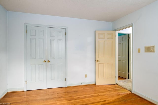unfurnished bedroom with a closet, baseboards, and light wood-style floors