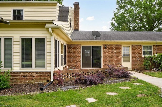 view of front of home with a front lawn, a chimney, and brick siding