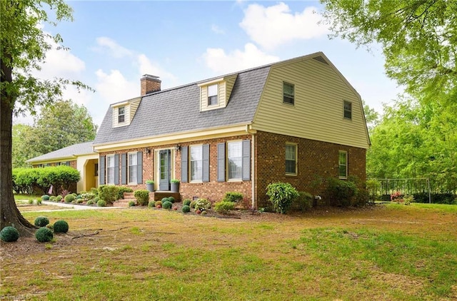 view of front of property featuring a front lawn, a chimney, a gambrel roof, and brick siding