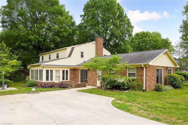 view of front of house featuring a front yard, a chimney, and brick siding