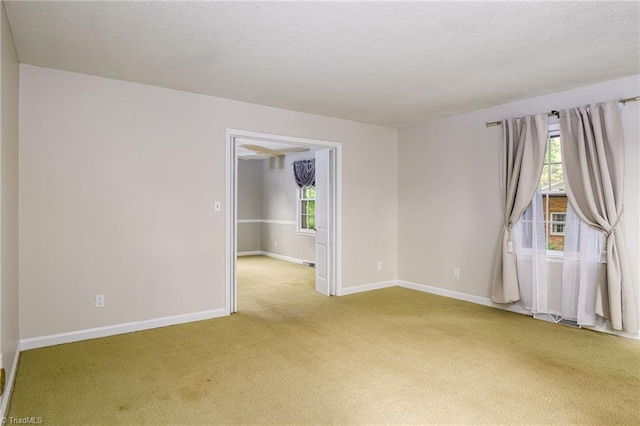 carpeted spare room featuring a textured ceiling and baseboards