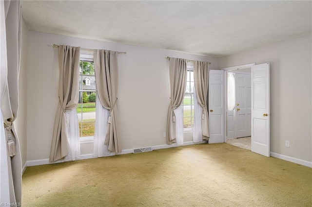 empty room with carpet flooring, visible vents, and baseboards