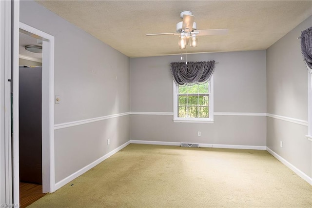 carpeted empty room with baseboards, visible vents, a ceiling fan, and a textured ceiling